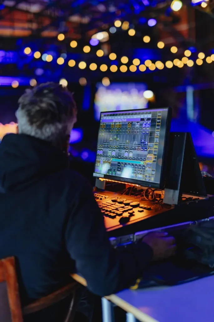 Techniker steuert Licht- und Tonregie an einem Mischpult während einer Live-Veranstaltung.