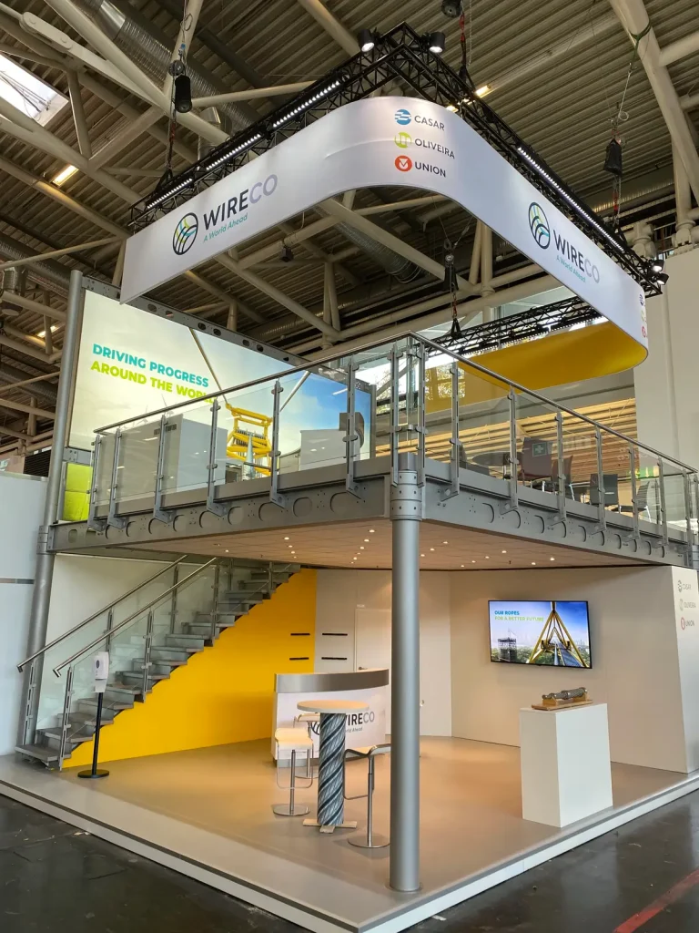 Zweigeschossiger WireCo-Messestand mit Galerie-Ebene, Treppe und Lounge-Bereich.